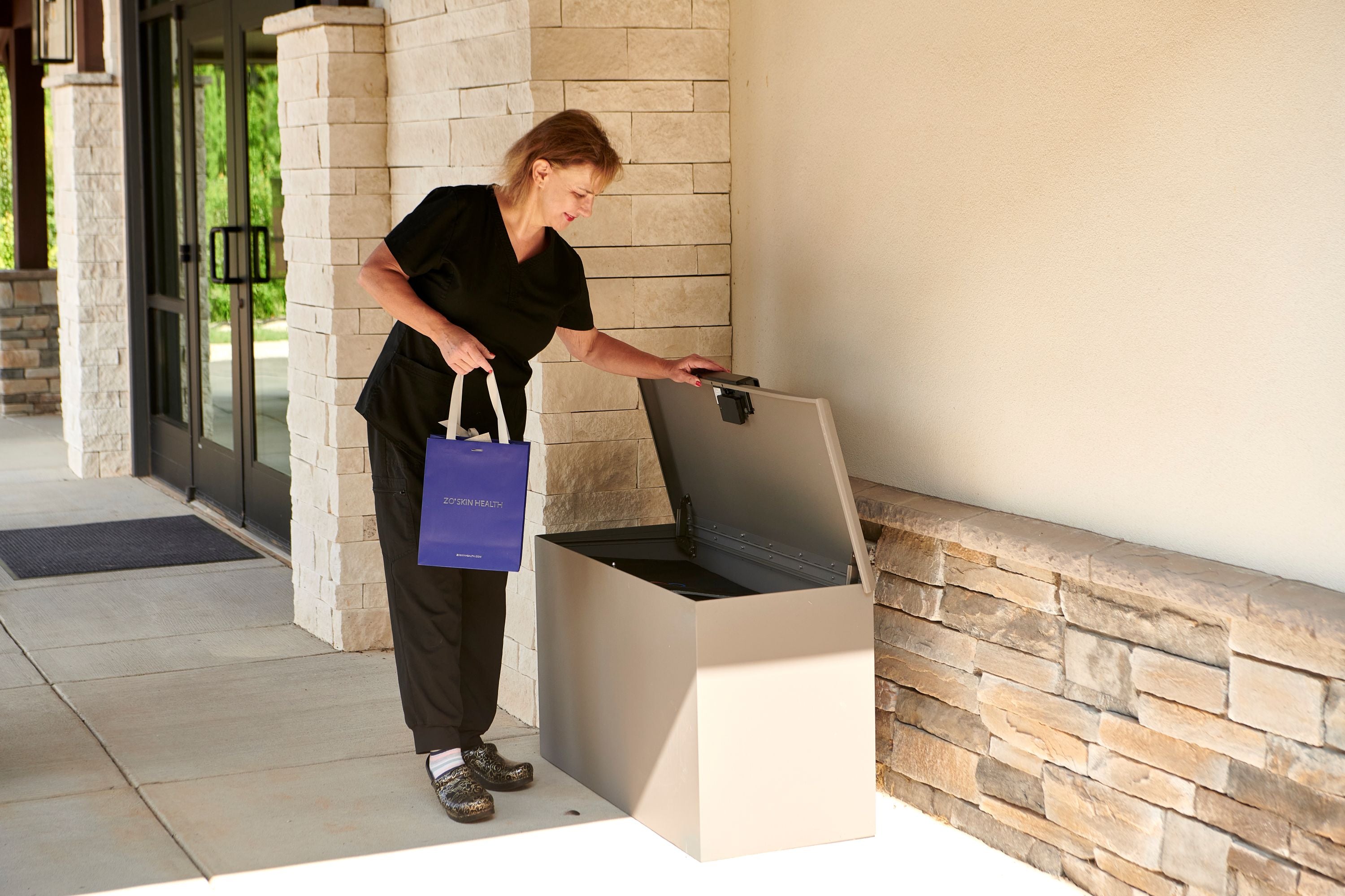 Small Business employee using a smart LOXX BOXX  with a blue bag in front of office.
