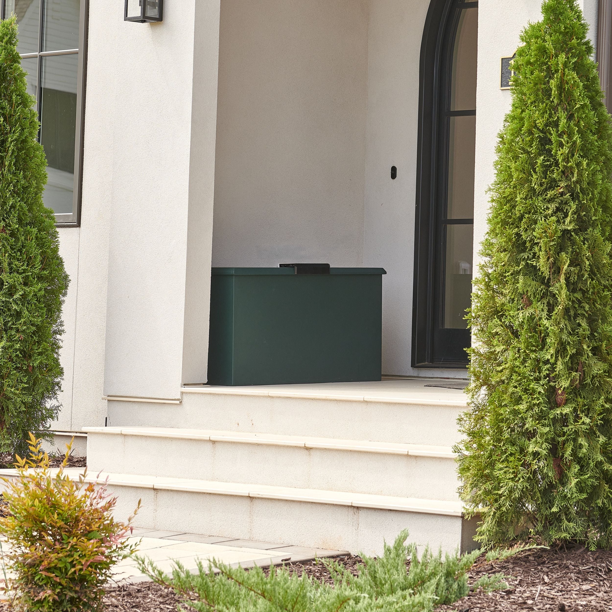 Green Loxx Boxx on a white porch with greenery around