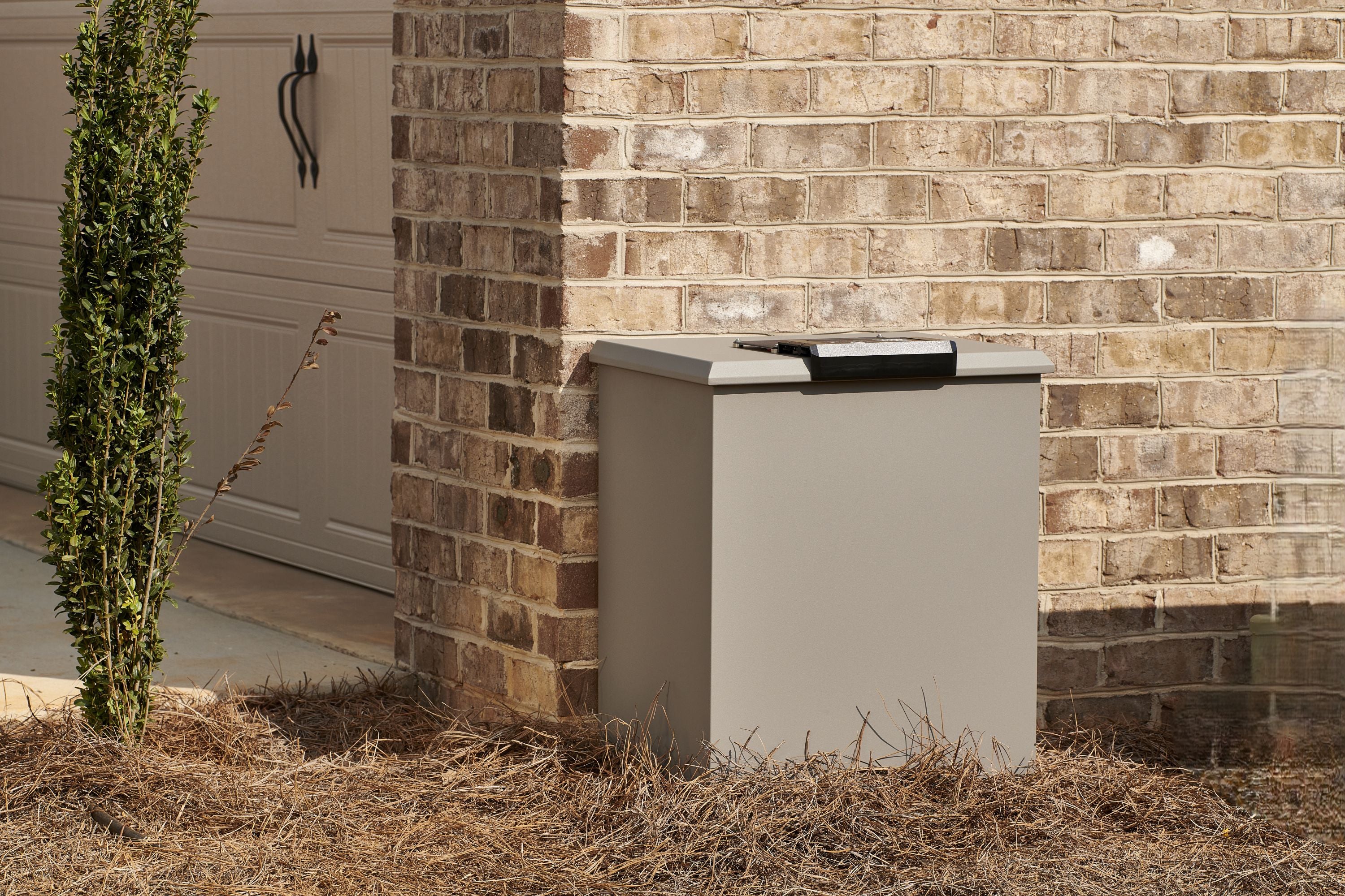 Loxx Boxx gray, Large against a brick wall with a garage door in the background